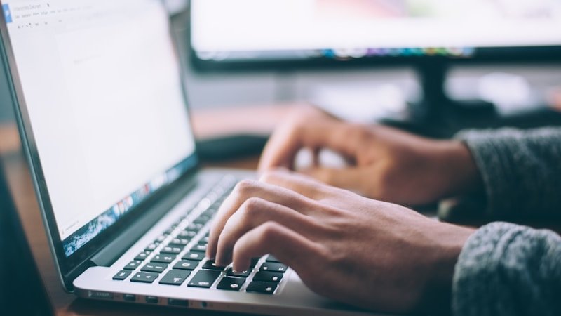 Person working at a simple home office desk with laptop